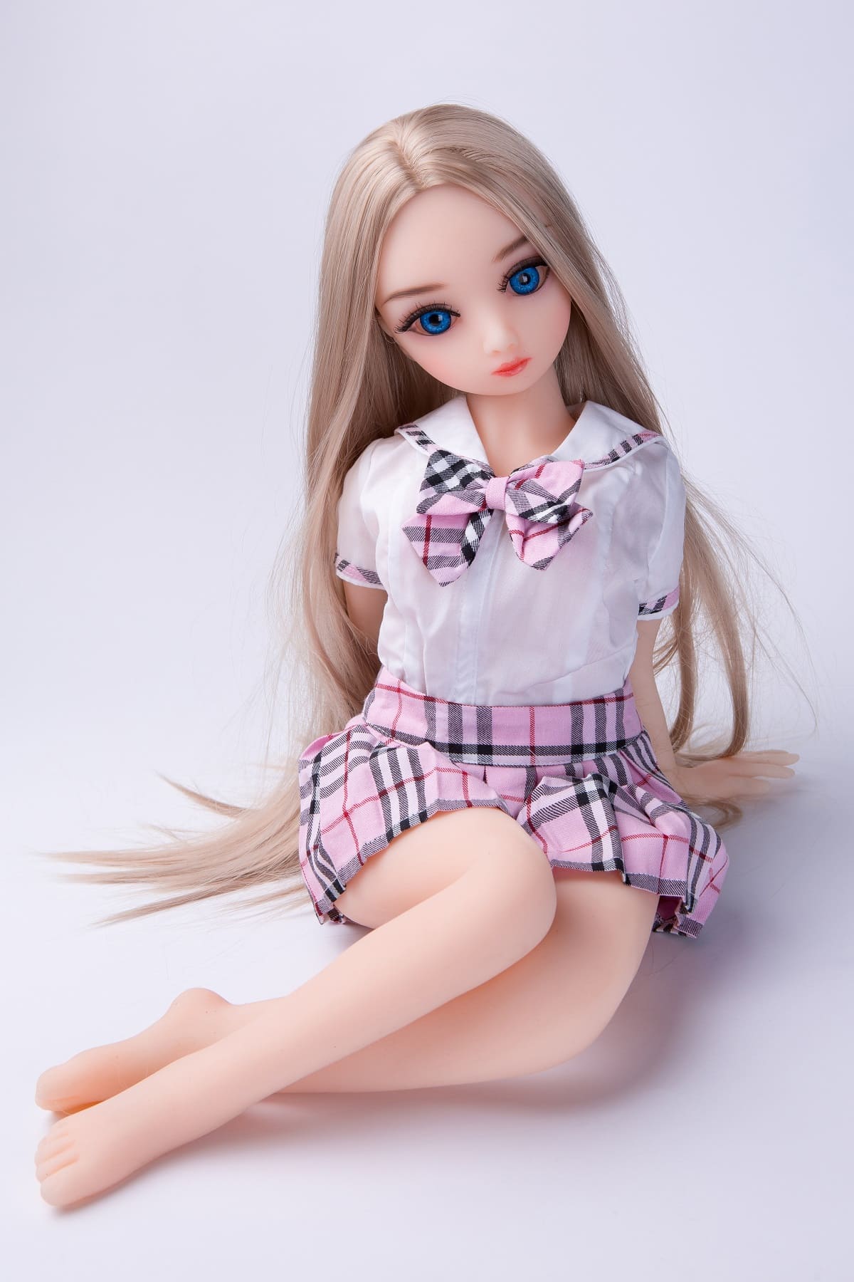 Miniature sex doll wearing a pleated school uniform